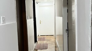 A hallway with a shiny tiled floor, a door at the end, and a striped mat in the center. - Cozy Central Room, Shared Bath & Kitchen (Abu Dhabi)