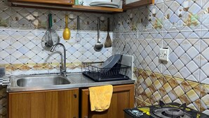 A kitchen with wooden cabinets, a sink, a stove, and a tiled backsplash. - Cozy Central Room, Shared Bath & Kitchen (Abu Dhabi)