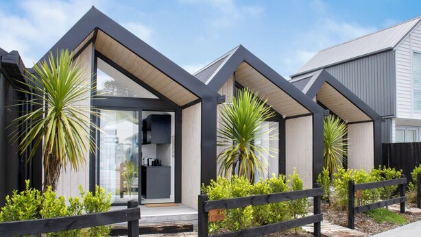 A modern house with a unique triangular roof design, large windows, and a wooden fence. - Gorgeous & Relaxing in Matakana (Matakana)
