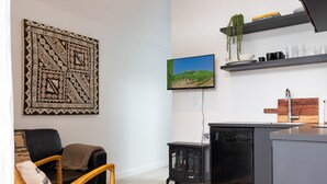 A modern kitchen with a built-in dishwasher, a flat-screen TV, and a hanging plant. - Gorgeous & Relaxing in Matakana (Matakana)