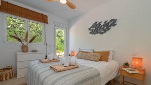 A bedroom with a bed, bedside table, lamp, and a wall art piece. - Los Jazmines - Javea, Costa Blanca (Javea)