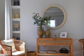 A room with wicker furniture, a round mirror, and a bookshelf with books and decorative items.