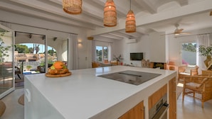 A modern kitchen with a large island, wicker pendant lights, and a view of the outdoors. - Los Jazmines - Javea, Costa Blanca (Javea)