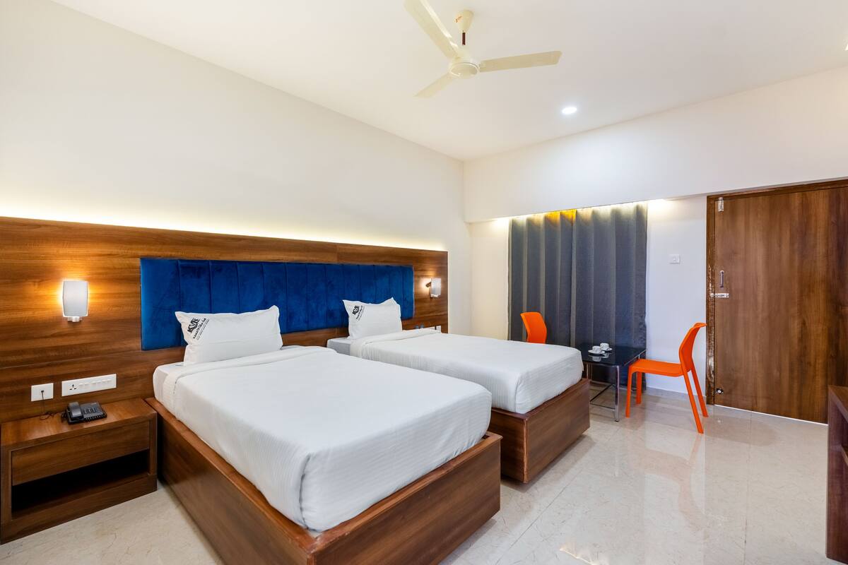 Habitación de hotel con dos camas, un escritorio, una silla y un armario.