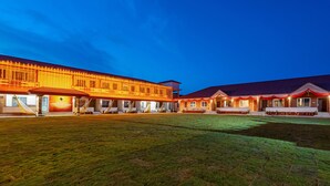 Un edificio grande con varias estructuras conectadas, un patio central y un césped bien cuidado.