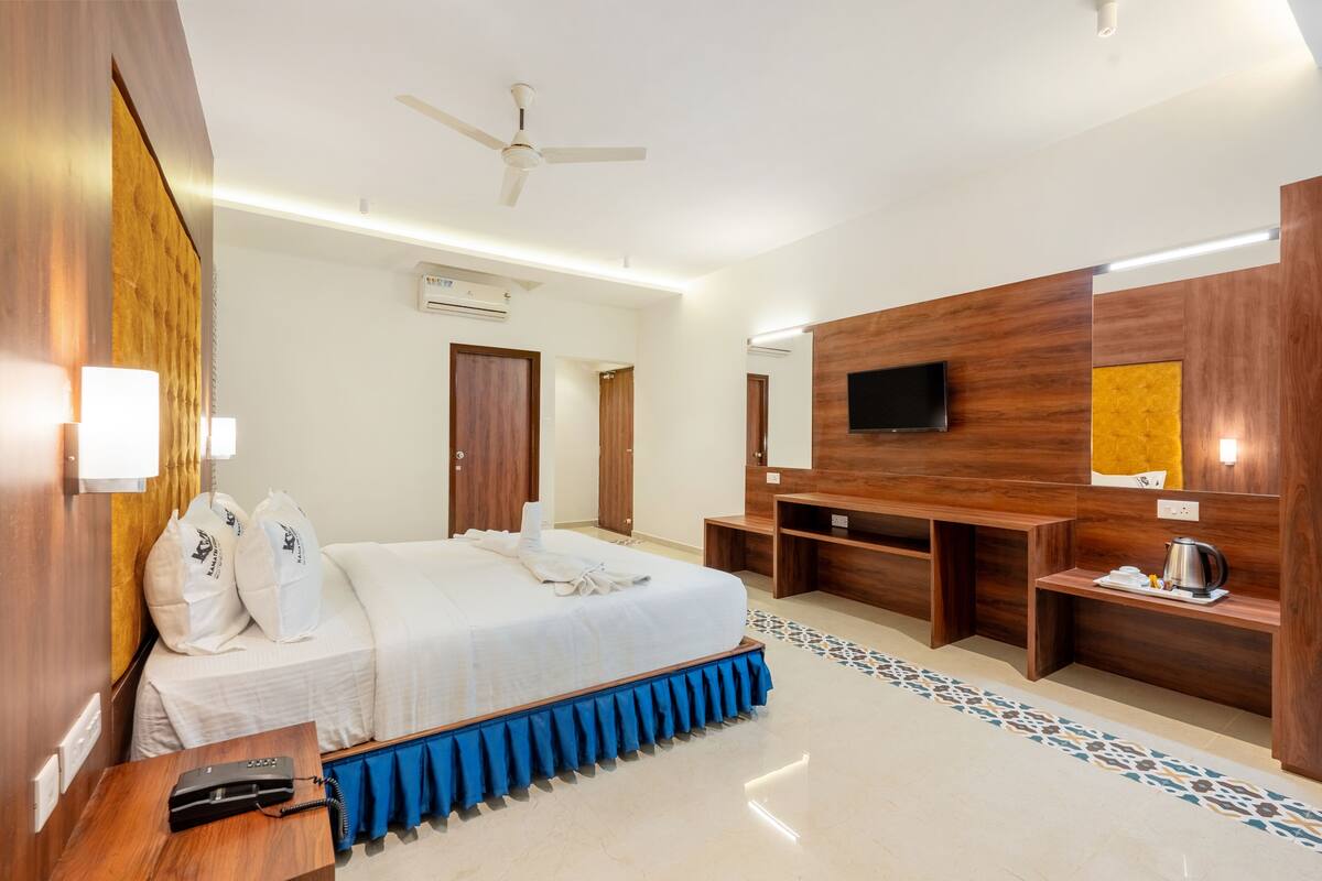Una habitación de hotel con cama, escritorio, teléfono, televisor y ventilador de techo.