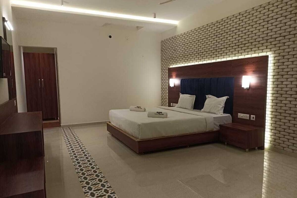 Un dormitorio moderno con una cama grande, una mesita de noche de madera, un cabecero con iluminación integrada, una alfombra estampada y un armario.