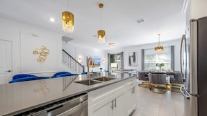 A modern kitchen with stainless steel appliances, a central island, and pendant lighting.
