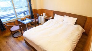 A hotel room with a wooden bed, a desk, a chair, a small table, and a window with curtains. - ryobou hanaemi (Otaru)
