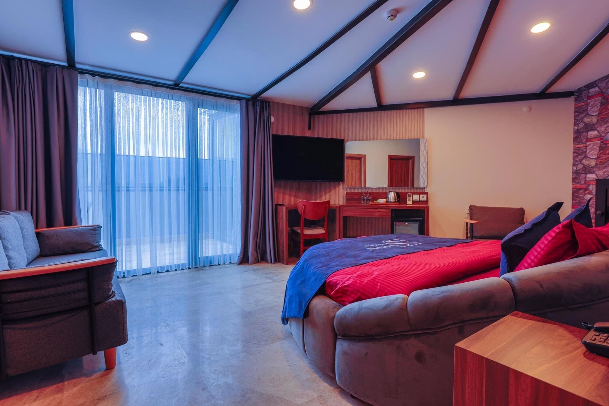 Una habitación de hotel moderna con una cama grande, un escritorio, un televisor y un rincón de descanso.