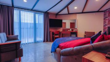 Una habitación de hotel moderna con una cama grande, un escritorio, un televisor y un rincón de descanso.