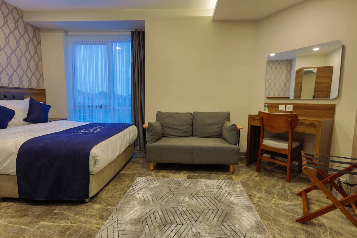 Une chambre d’hôtel avec un lit, un canapé, un bureau et une chaise.
