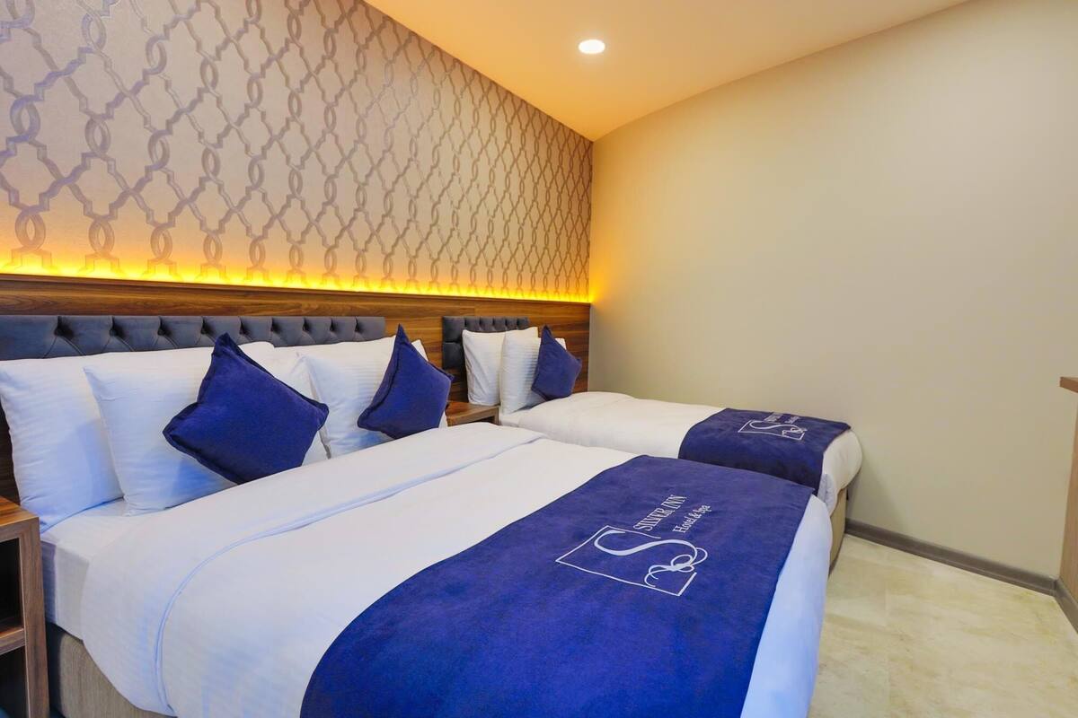 Une chambre d’hôtel avec deux lits, un mur à motifs et une tête de lit en bois.
