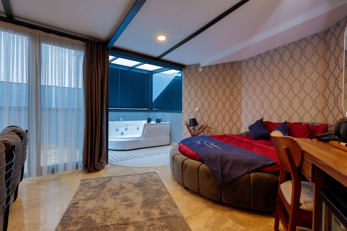 Une chambre moderne avec un grand lit, un bureau en bois et une baignoire intégrée.