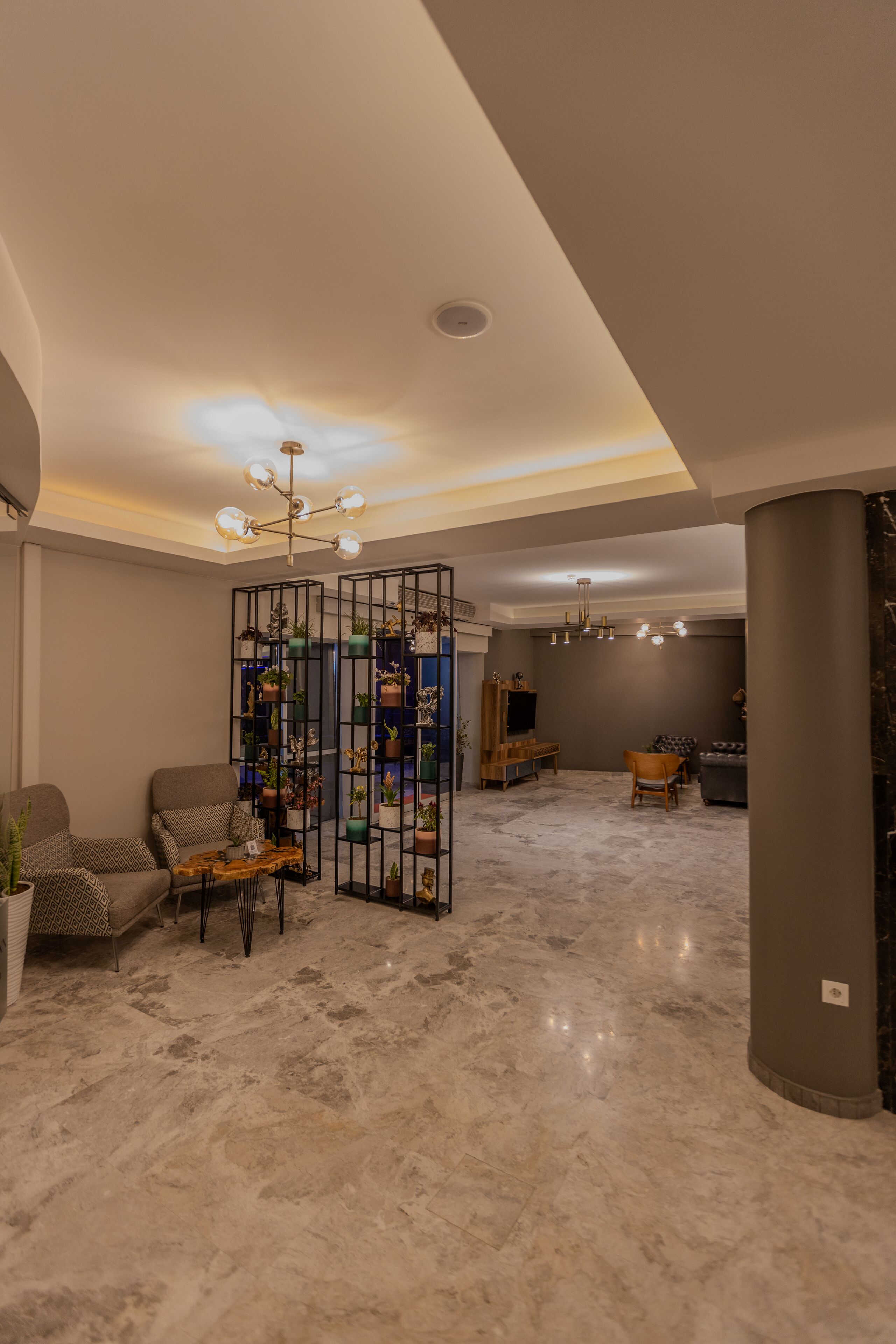 A modern living room with a marble floor, a sectional sofa, a coffee table, and a decorative plant wall.