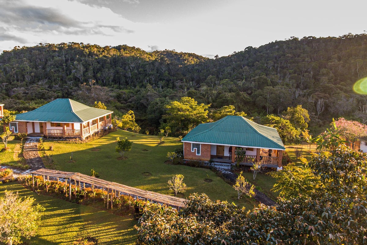 Um conjunto de casas com telhados verdes, cercado por vegetação exuberante e colinas.