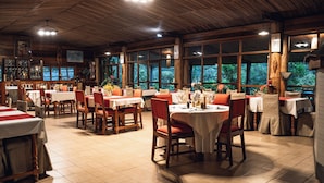 A restaurant with wooden interiors, large windows, and tables set for dining. - Eulophiella (Andasibe)