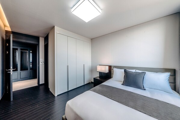 A modern hotel room with a large bed, a wardrobe, a nightstand, and a ceiling light.