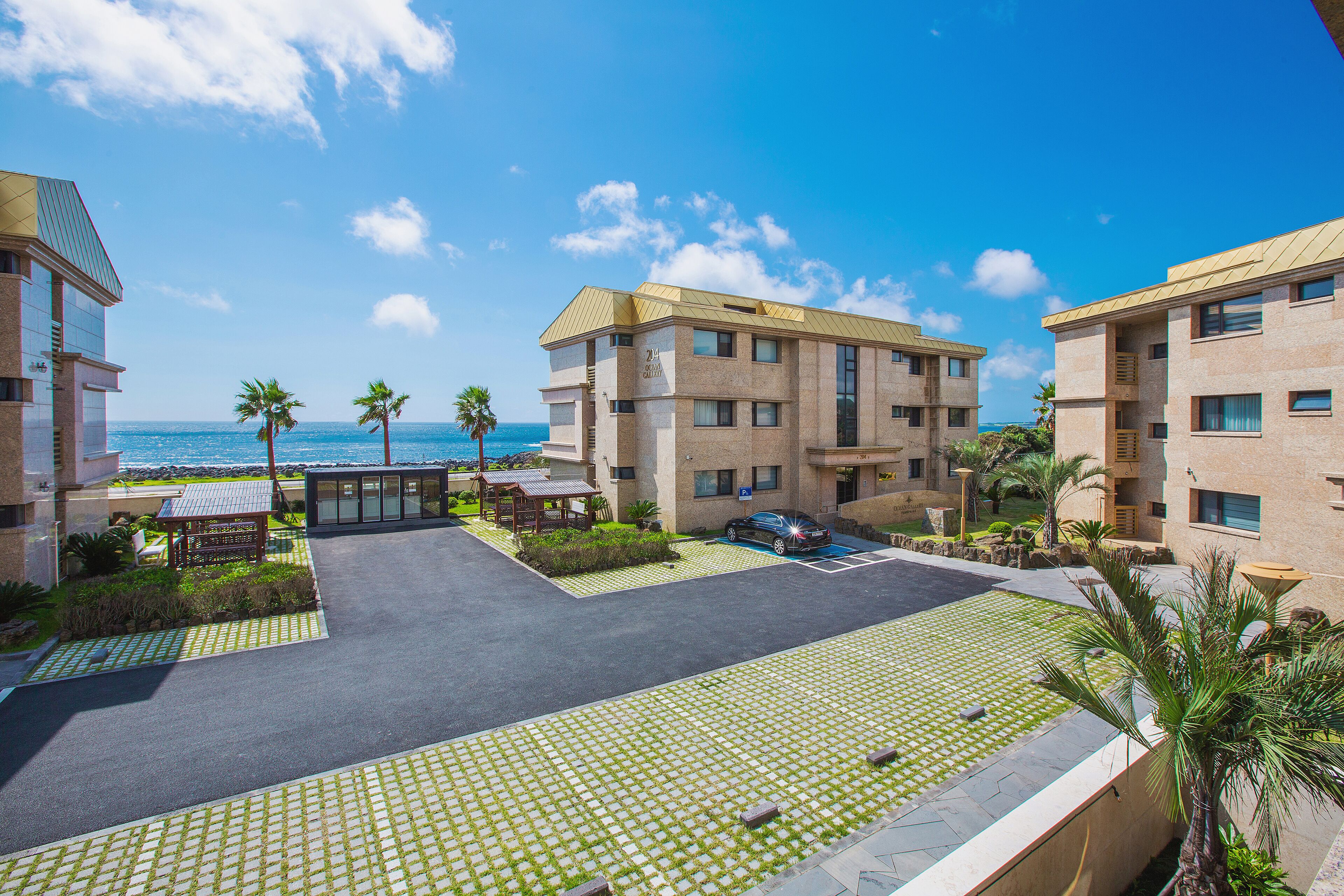 A hotel courtyard with a paved area, palm trees, and a view of the ocean.