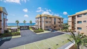 A hotel courtyard with a paved area, palm trees, and a view of the ocean.