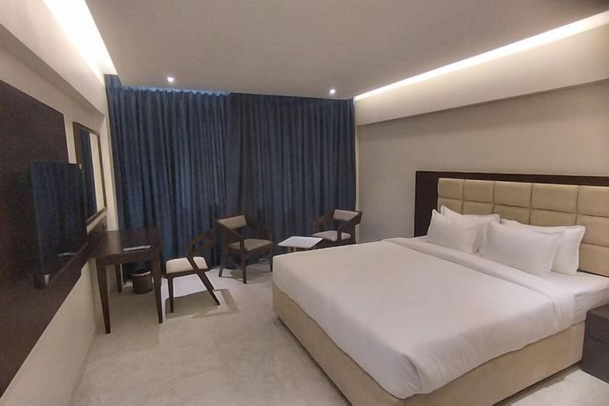 Une chambre d’hôtel avec un grand lit, un bureau avec deux chaises, une petite table et un miroir.