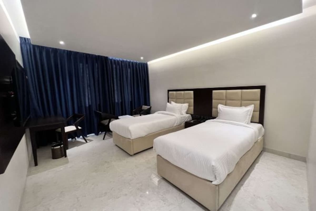 Une chambre d’hôtel avec deux lits, un bureau et une chaise.
