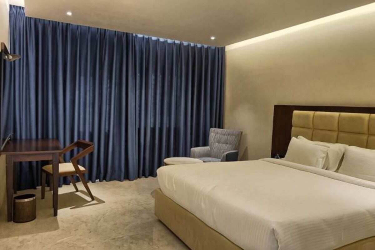 Une chambre d’hôtel avec un lit, un bureau, une chaise et un rideau.