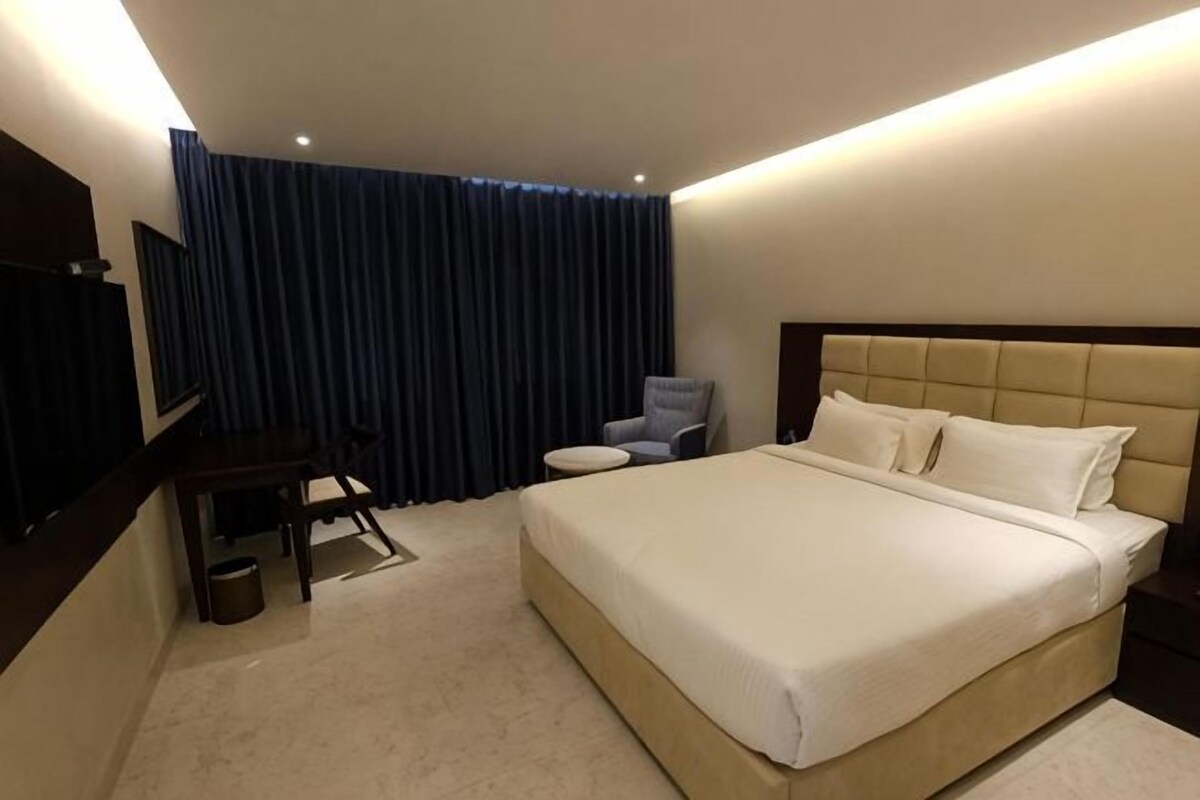 Une chambre d’hôtel avec un grand lit, un bureau, une chaise et un téléviseur.