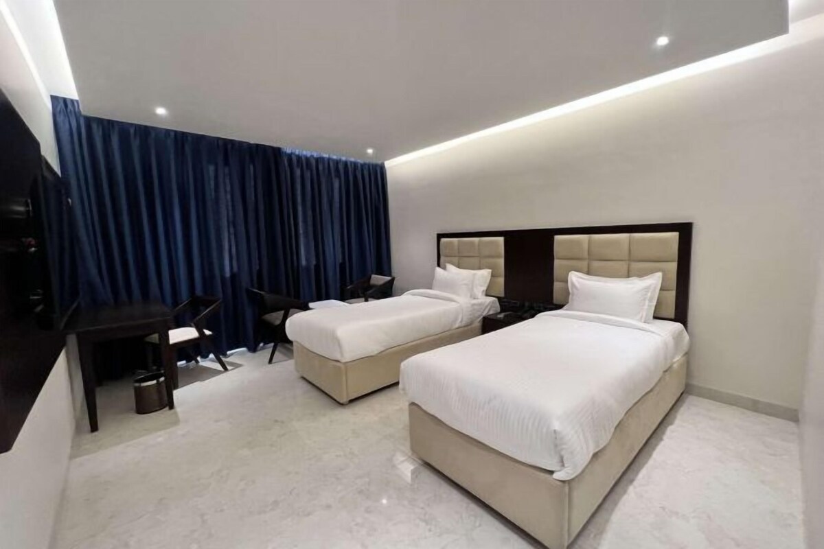 Une chambre d’hôtel avec deux lits, un bureau et une chaise.