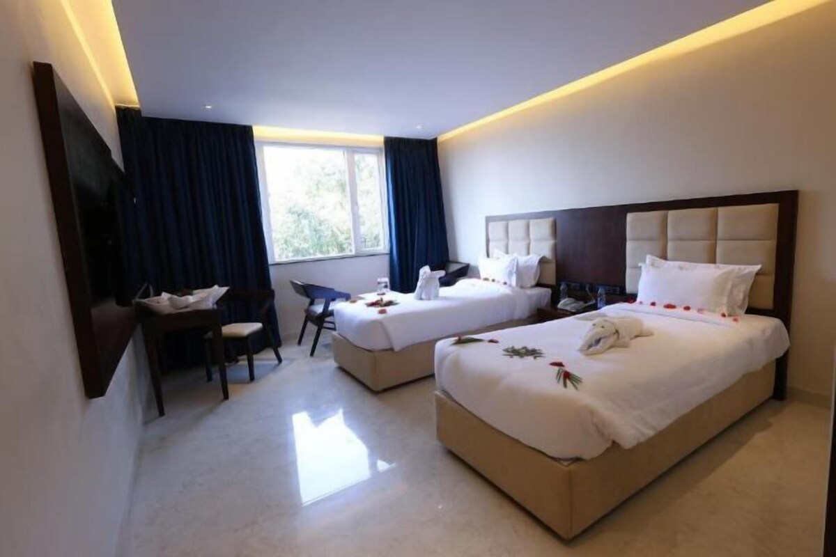 Une chambre d’hôtel avec deux lits, un bureau et une chaise.