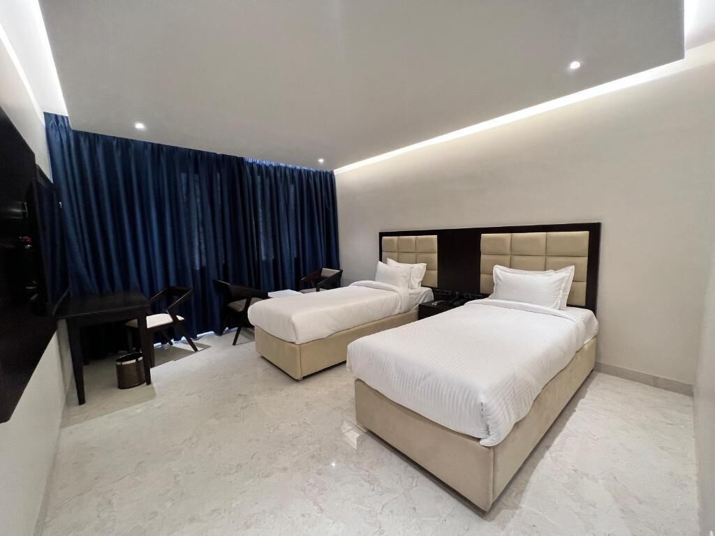 A hotel room with two beds, a desk, and a chair.