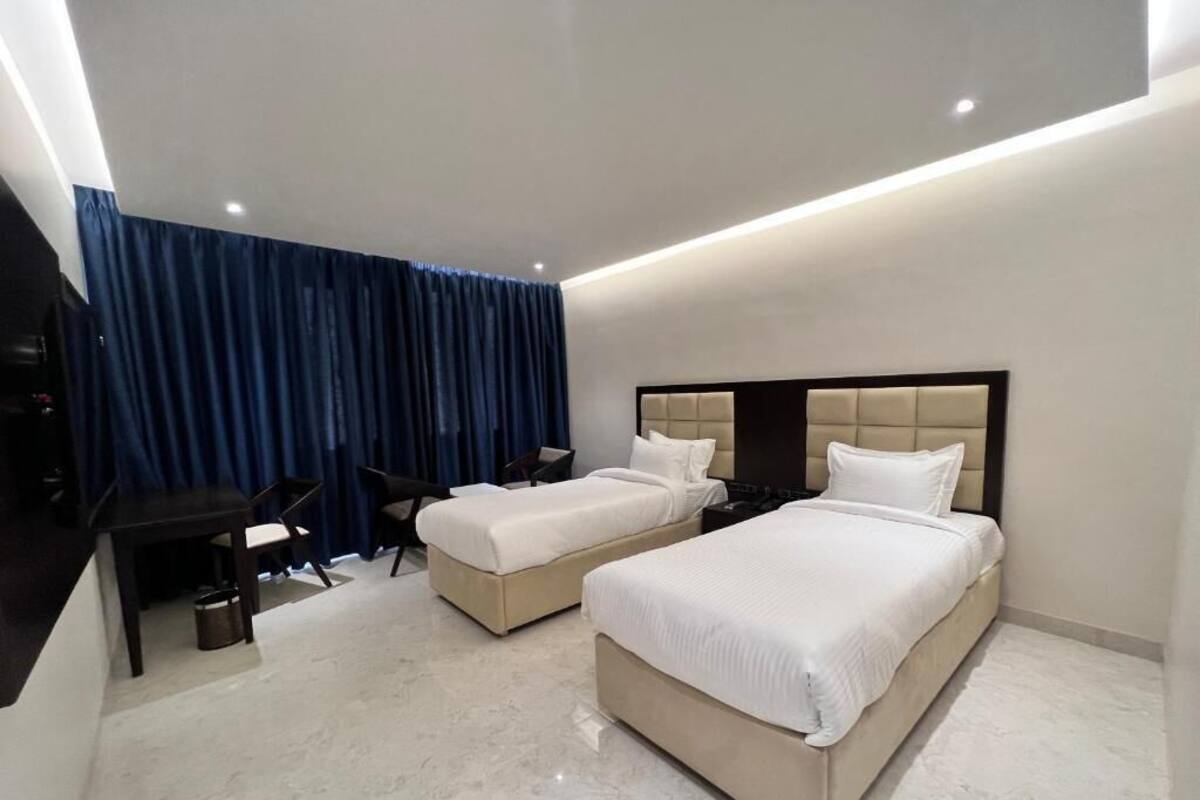 Une chambre d’hôtel avec deux lits, un bureau et une chaise.