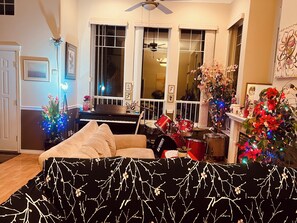 A living room with a piano, a drum set, a sofa, and a Christmas tree.