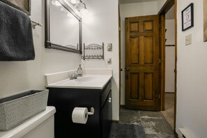 A bathroom with a white sink, black vanity, and a wooden door.