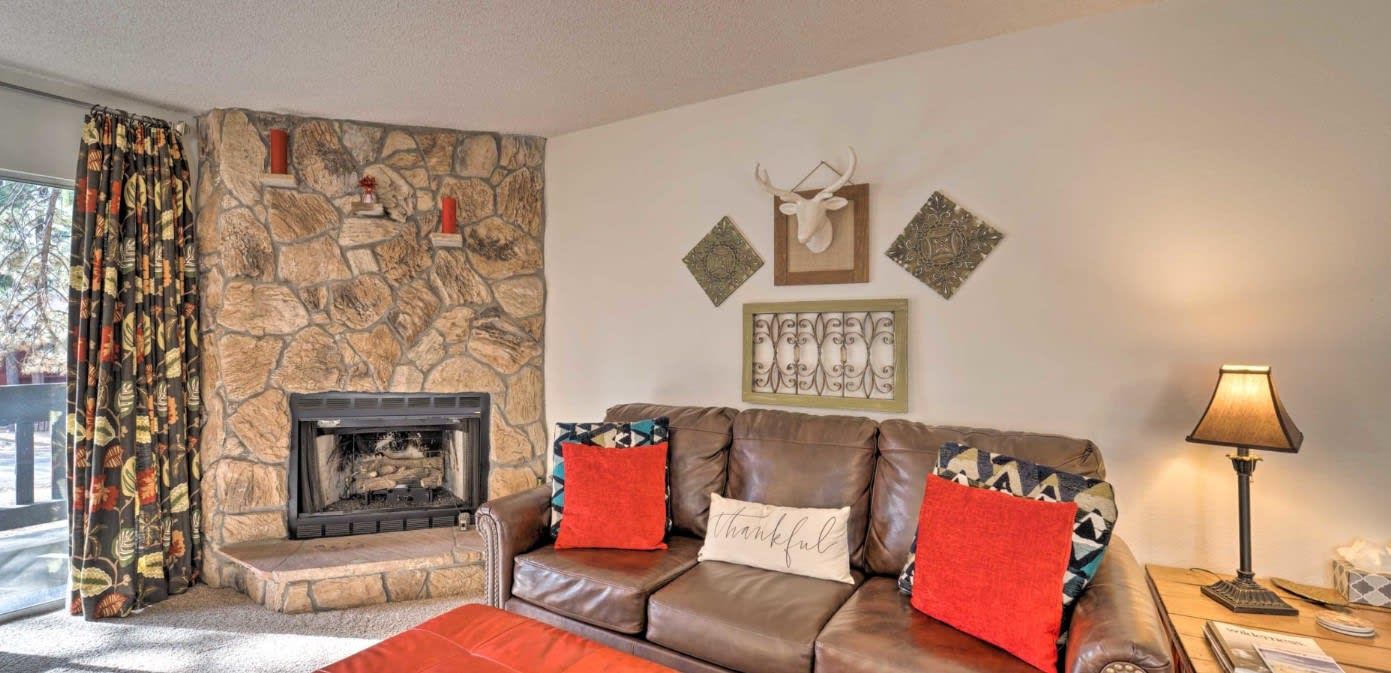 Una sala de estar acogedora con una chimenea de piedra, un sofá de cuero y detalles decorativos en las paredes.