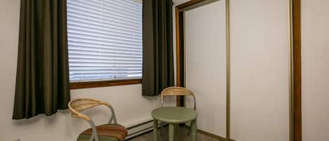 Et værelse med et vindue, to stole, en radiator og en dør.