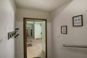 A hallway with a door leading to a room, a handrail on the right, and two signs on the wall. - Angel Fire Condo Mountain Retreat by Velo (Angel Fire)