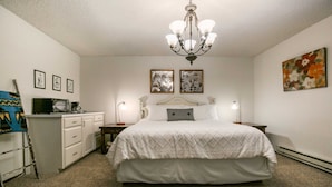 A bedroom with a bed, a dresser, a chair, and a chandelier. - Angel Fire Condo Mountain Retreat by Velo (Angel Fire)