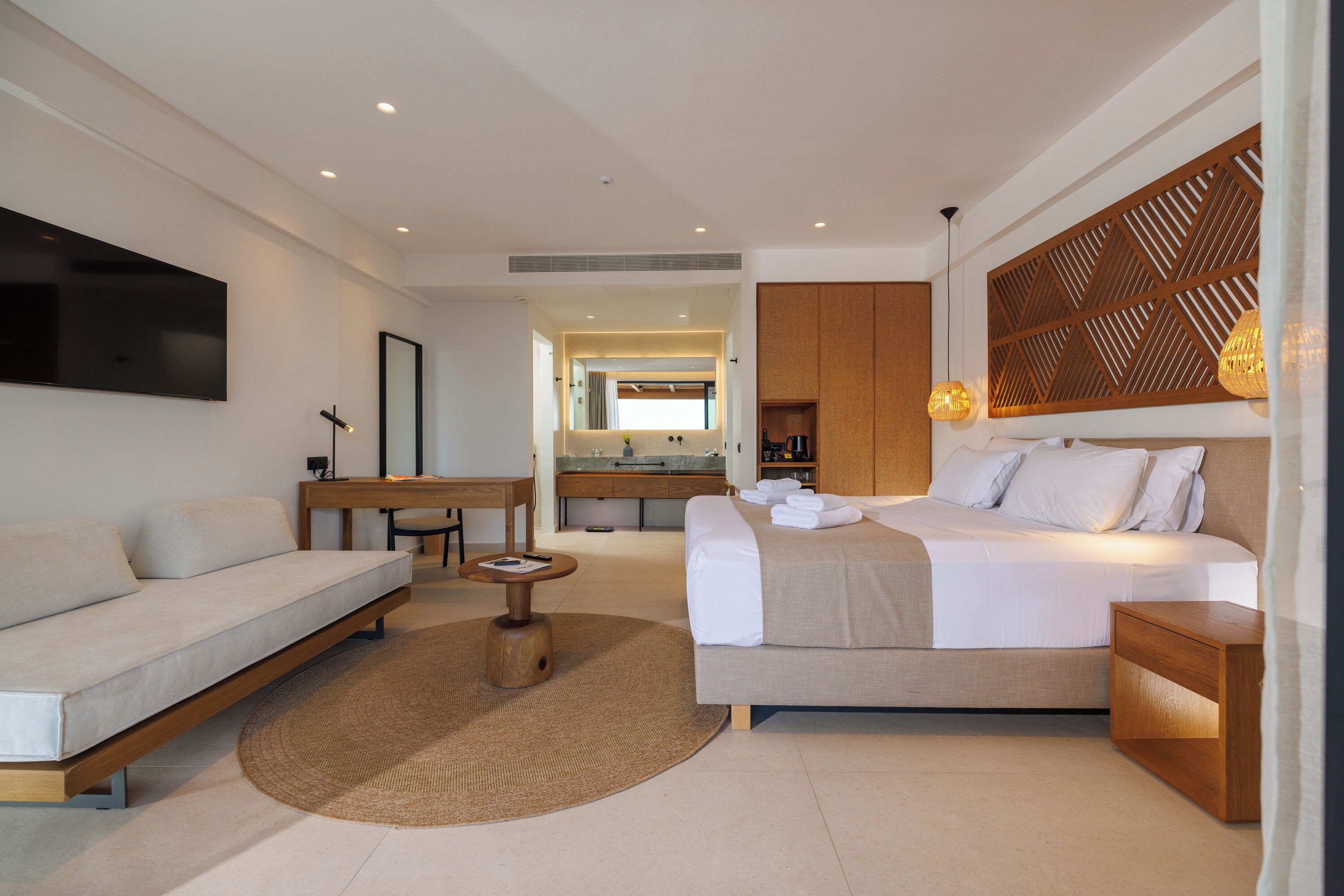 A modern hotel room with a sofa, a bed, a desk, and a small round table.