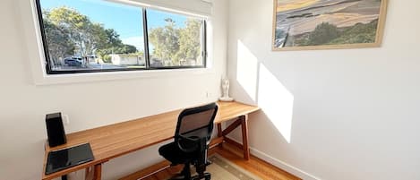 Een kamer met een bureau, stoel en een schilderij aan de muur.