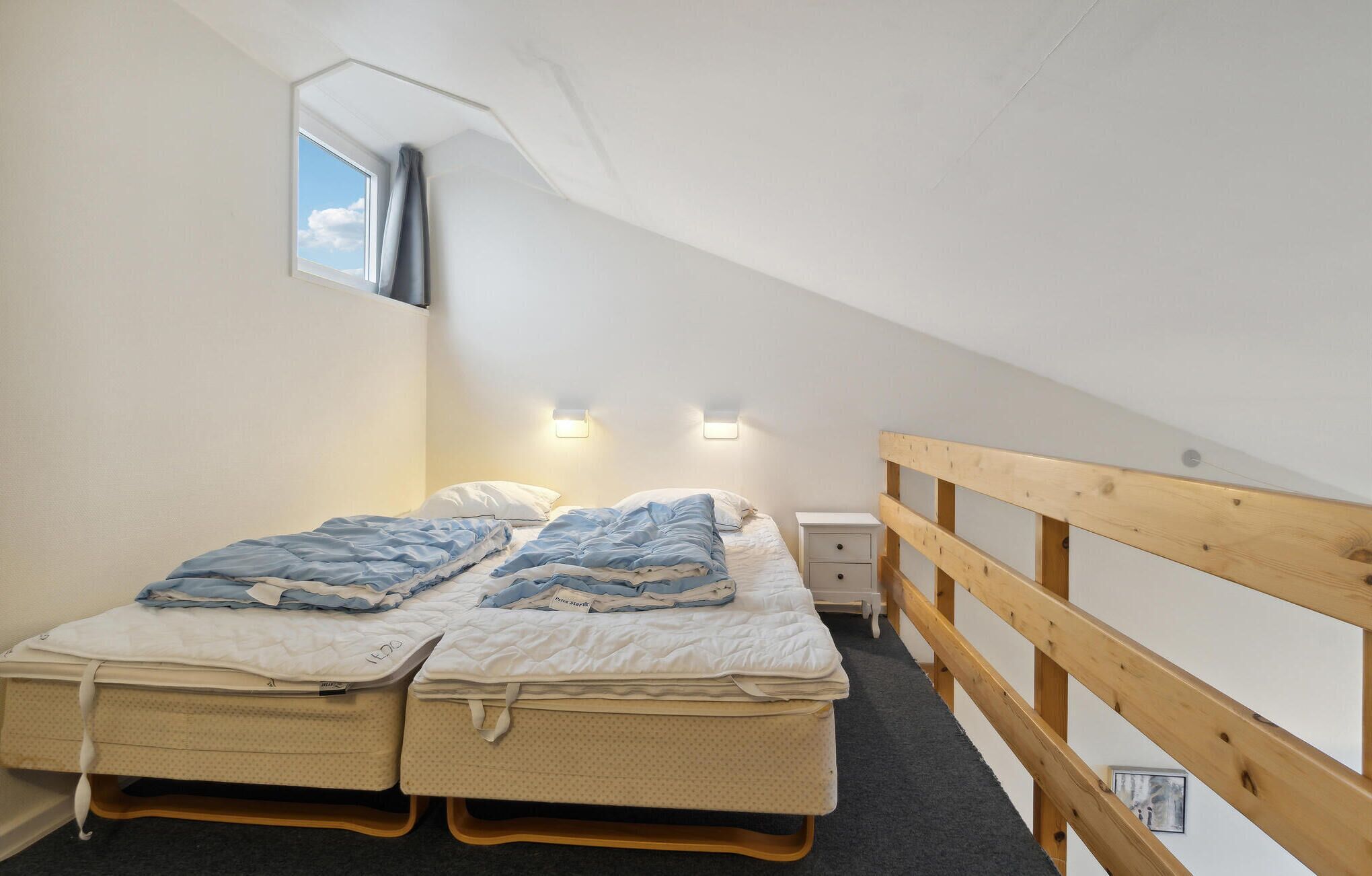 Un dormitorio acogedor en un ático, con dos camas literas, baranda de madera y un tragaluz.