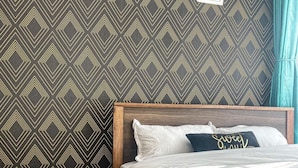A neatly made bed with a wooden headboard, a small round table with a remote control, and a patterned rug on the floor. - Jiji poa (Nairobi)