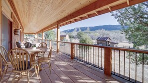 Une terrasse en bois avec une table et des chaises, offrant une vue sur un paysage montagneux.