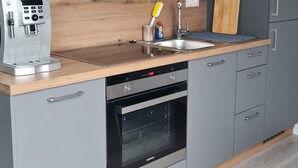 Eine moderne Küche mit grauen Schränken, einer Holz Arbeitsplatte, einer Kaffeemaschine, einem Spülbecken und einem Geschirrspüler.