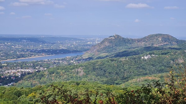 Vista panorámica de un pueblo costero con una colina destacada, un río y un puente a lo lejos.
