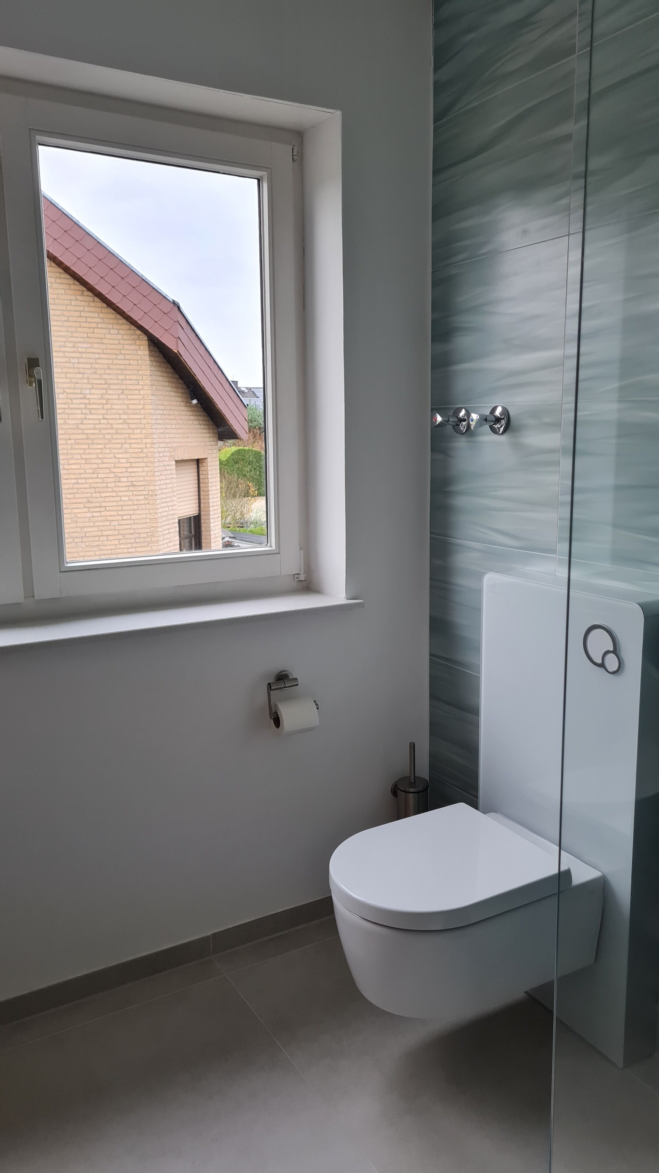 A bathroom with a toilet, a window, and a glass shower enclosure.