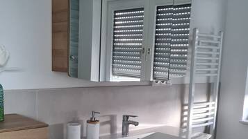 A modern bathroom with a wooden vanity, a large mirror, and a built-in heater.
