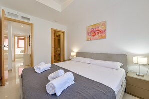 Een hotelkamer met een bed, twee bedlampen, een schilderij aan de muur en een deur naar een badkamer.