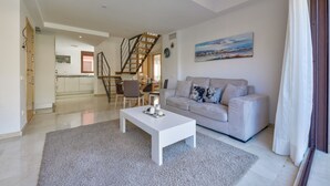 A modern living room with a white sofa, a coffee table, and a staircase leading to an upper floor.