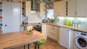 A kitchen with wooden countertops, a built-in oven, a washing machine, and a variety of cabinets. - 27 Garenin (Isle of Lewis)
